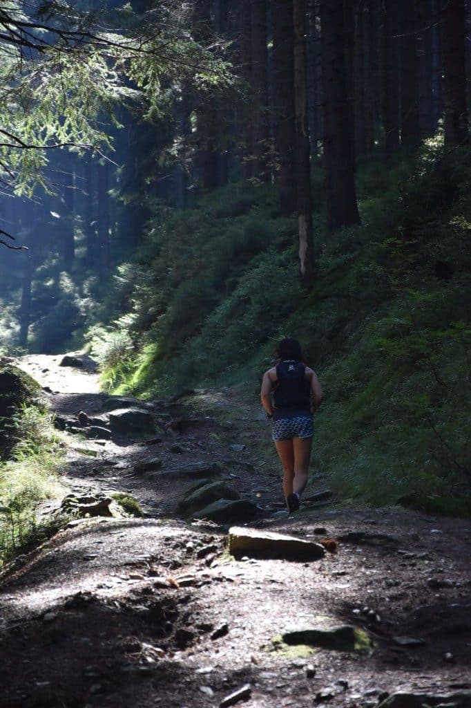 Läuferin mit Rucksack auf einem steinigen Waldpfad