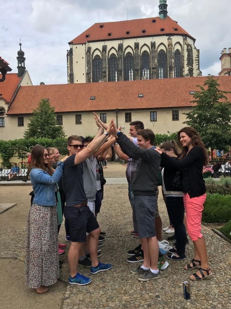 Schüler bilden mit erhobenen Armen einen Tunnel auf einem Hof vor einem gotischen Gebäude