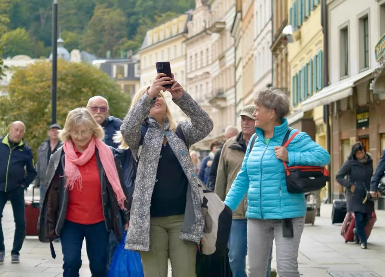Reisegruppe in Karlsbad, eine Frau fotografiert die Straße mit dem Handy