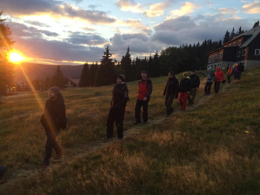 Konferenzteilnehmer gehen bei Sonnenuntergang einen grasbewachsenen Hang zum Berghotel hinunter